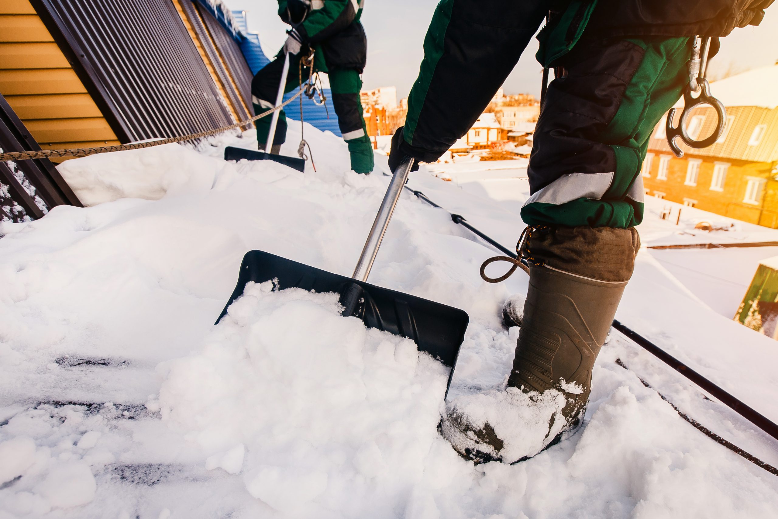 Cleaning roofs of buildings from snow, ice in the winter with a shovel is snow removal services